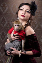 Retro female portrait in the style of 20s or 30s. A gorgeous lady is holding a little monkey.