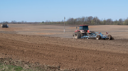 Spring field work. The tractor plows the ground. Preparation for sowing agricultural crops. Farming. Horizontal photo. 