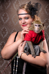 Retro female portrait in the style of 20s or 30s. A gorgeous lady is holding a little monkey.