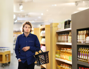 Young man shopping in supermarket, reading product information