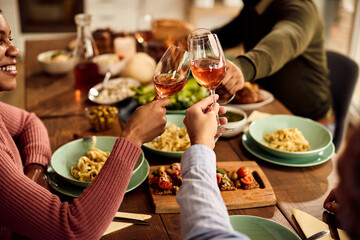 Close-up of friends toasting with wine during lunch at dining table.