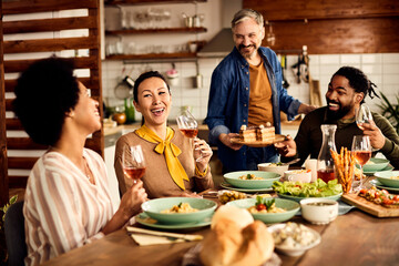Multi-ethic group of friends having fun during a meal at dining table.