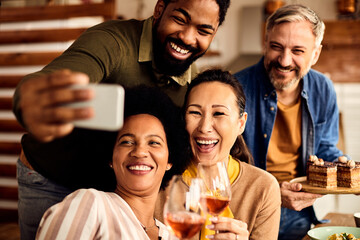 Multi-ethnic group of cheerful friends having fun while taking selfie with smart phone.