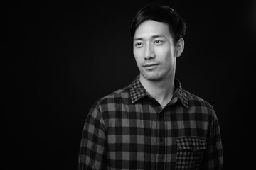 Young handsome Asian man against black background