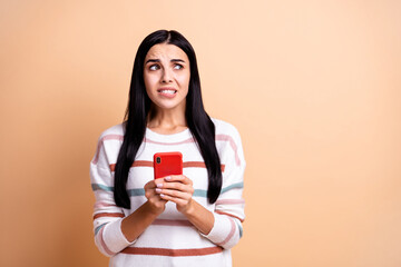Photo of young nervous girl worried bite lips teeth fail use smartphone look empty space isolated...