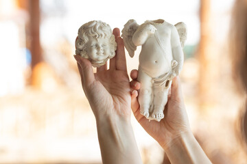 a woman holding a broken angel figurine - body and head