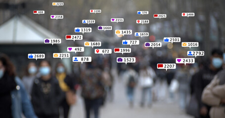 Group of out-of-focus pedestrians walking through the streets of a city while emoticons and notification animations appear on the screen. Concept: urban life	