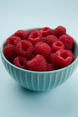 raspberries in a bowl on a colored background