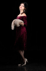 A beautiful girl dressed in the style of the 20-30s of the last century posing on a dark background.