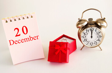 calendar date on light background with red gift box with ring and alarm clock with copy space. December 20 is the twentieth day of the month