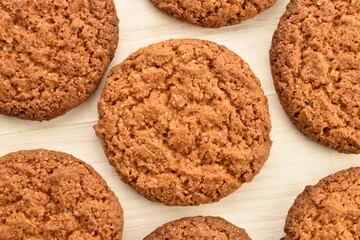 Several dark brown oatmeal cookies on a wooden table, close-up, top view.