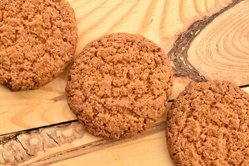 Several dark brown oatmeal cookies on a wooden table, close-up, top view.