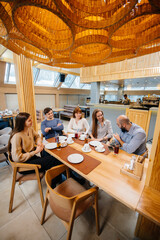 A group of young cheerful friends is sitting in a cafe talking and eating pizza. Lunch at the pizzeria.