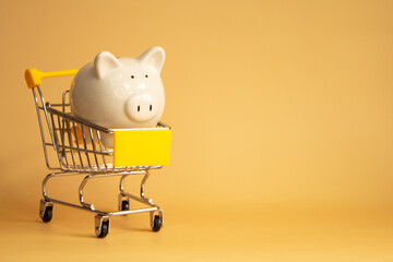 Piggybank is a yellow cart. Saving money, spend economically. Shopping for products online. And financial management An object on a yellow background