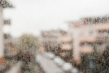 Blur background with bokeh drops of rain on a window pane, big city. Raindrops on window glass