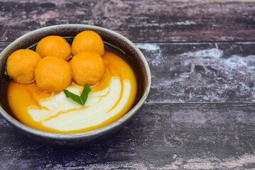 Bubur Sumsum Biji Salak, Indonesian rice flour porridge with sweet potato glutinous rice balls, served with palm sugar sauce, garnish with pandan leaf. Popular food during Ramadan