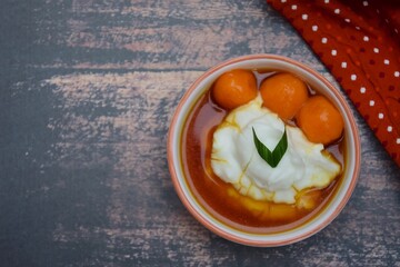 Bubur Sumsum Biji Salak, Indonesian rice flour porridge with sweet potato glutinous rice balls, served with palm sugar sauce, garnish with pandan leaf. Popular food during Ramadan