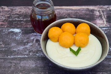 Bubur Sumsum Biji Salak, Indonesian rice flour porridge with sweet potato glutinous rice balls, served with palm sugar sauce, garnish with pandan leaf. Popular food during Ramadan