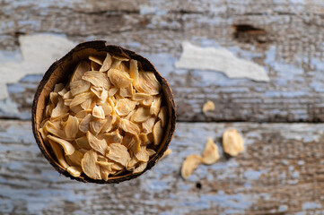fragrant dry garlic in flakes in a coconut bowl on an old wooden background, top view, empty space...