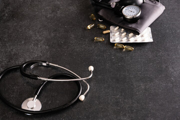 tonometer, pressure measuring device with pills on gray dark table, empty space for text