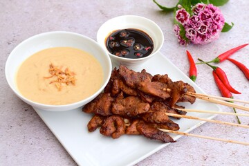 Sate Ayam or Chicken satay or Chicken skewers. Indonesian food. Served with peanut sauce, thick soy sauce and chili 