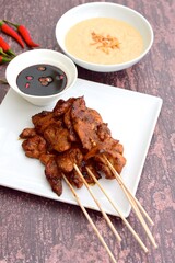 Sate Ayam or Chicken satay or Chicken skewers. Indonesian food. Served with peanut sauce, thick soy sauce and chili 