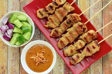 Indonesian chicken satay or Sate Ayam. Served with peanut sauce and pickles cucumber and onion