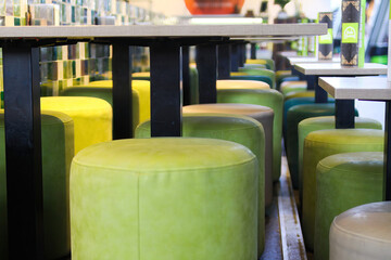 Rotterdam, Netherlands - November 9. 2018: View on empty modern green yellow leather stools and...