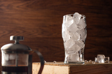 glass filled with ice on wooden background