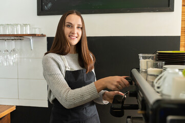 Fototapeta na wymiar Female barista wearing apron preparing coffee in a cafe, professional coffee brewing. Small business owner, waitress