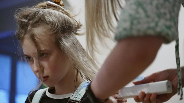 Mom cuts her daughter with a hair clipper at home.