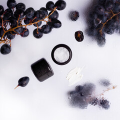Cosmetics cream on a white background next to the grapes. View from above. Copy space