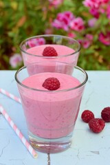 Raspberry smoothies with pink flowers on the background