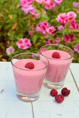 Raspberry smoothies with pink flowers on the background