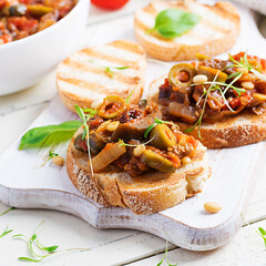 Traditional Italian Caponata and toast on a wooden white table. Sicilian caponata.