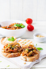 Traditional Italian Caponata and toast on a wooden white table. Sicilian caponata.