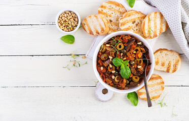 Traditional Italian Caponata and toast on a wooden white table. Sicilian caponata. Top view, above,...