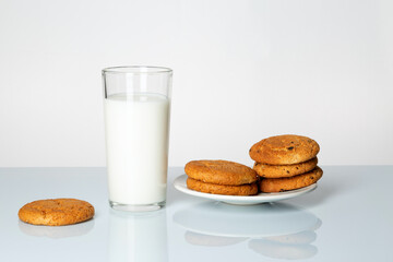 A glass of milk and cookies on a table on a white background.