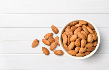 Flat lay (top view) of Close-up Almond seeds  in white bowl on white wood.