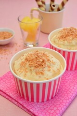 Pineapple coconut ice cream in cups topped with toasted coconut flakes