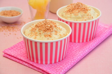 Pineapple coconut ice cream in cups topped with toasted coconut flakes