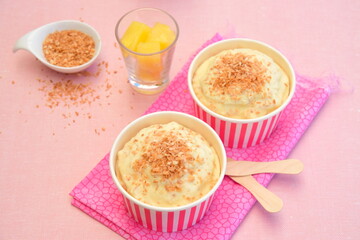 Pineapple coconut ice cream in cups topped with toasted coconut flakes