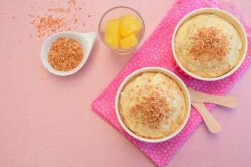 Pineapple coconut ice cream in cups topped with toasted coconut flakes
