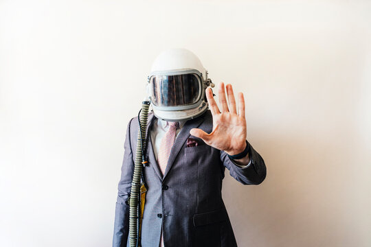 Businessman with astronaut helmet showing the palm of his hand
