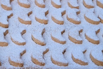 Putri Salju or crescent-shaped cookies coated with powdered sugar. Traditional Indonesian cookies to celebrate Eid al Fitr. Decorated with yellow flower on wooden background