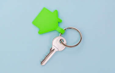 key chain with green house symbol and keys on blue background,Real estate concept