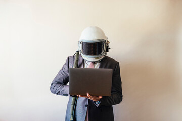 Businessman with astronaut helmet using a laptop © karrastock