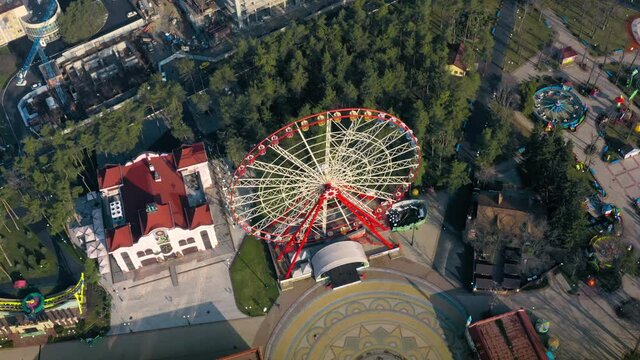 Aerial panorama of the Ferris wheel in the park in the morning on a spring dayl in the city during a national Covid-19 Lockdown. Empty park without tourists and visitors - aerial drone shot