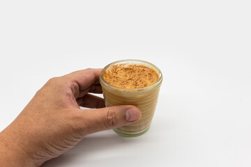 Hand holding dirty coffee on top of cold milk isolated on white