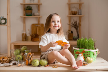 cute little girl eats natural pastille at home in a wooden kitchen. Food for children from natural products